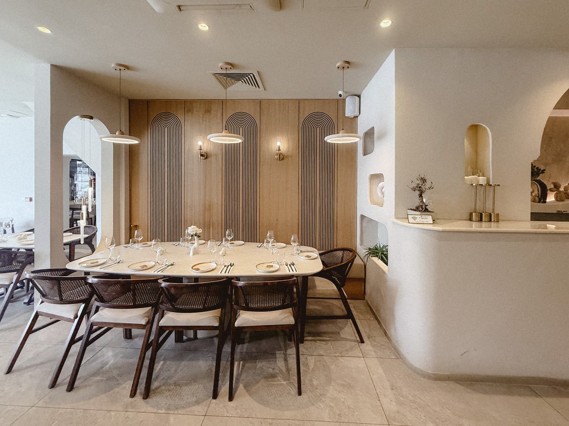 Private dining area at Monsieur with an oval marble table, cane-backed chairs and oak arch-panelled walls
