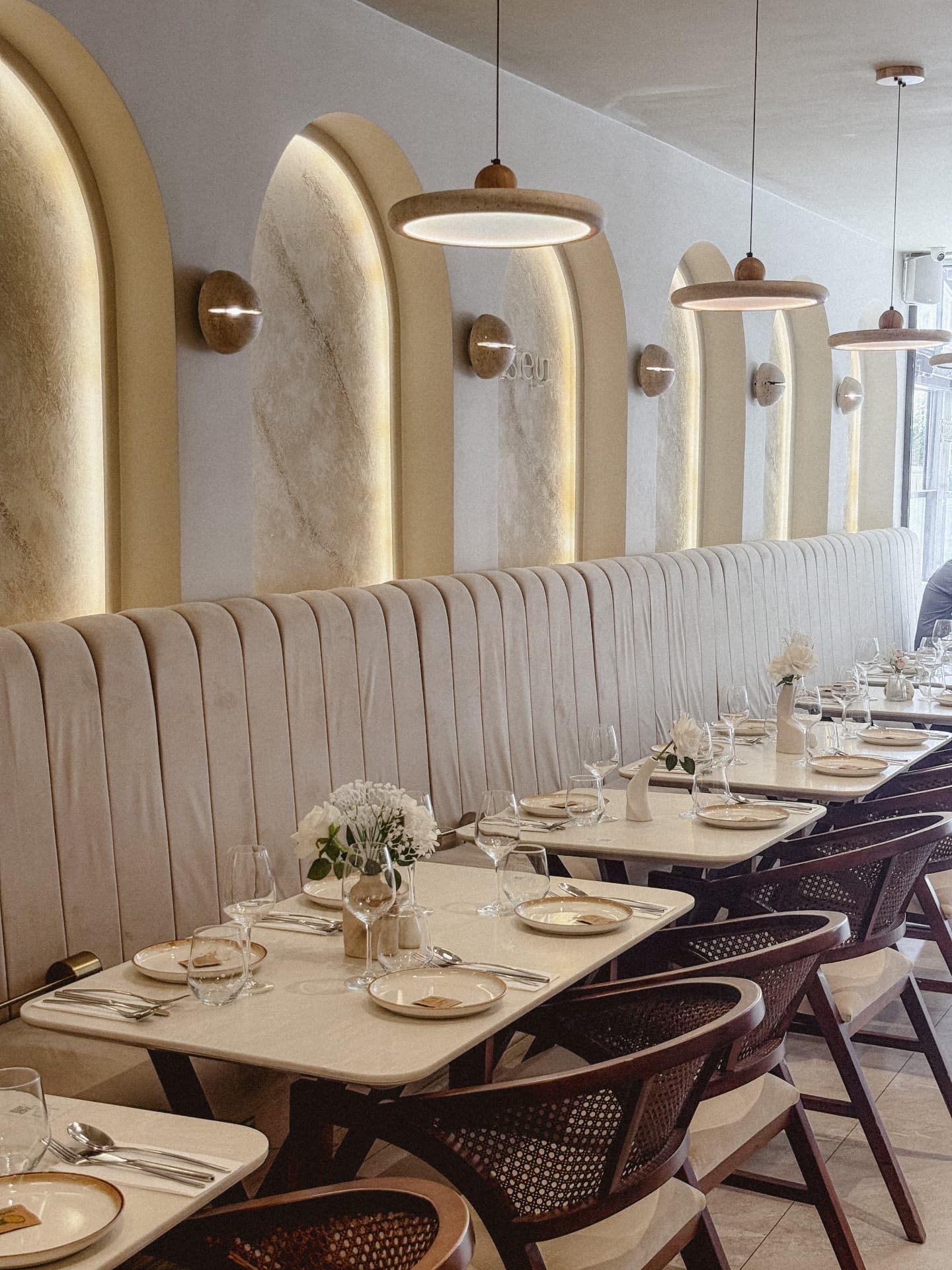 Illuminated plaster arches with the Monsieur sign, banquette seating and pendant lights